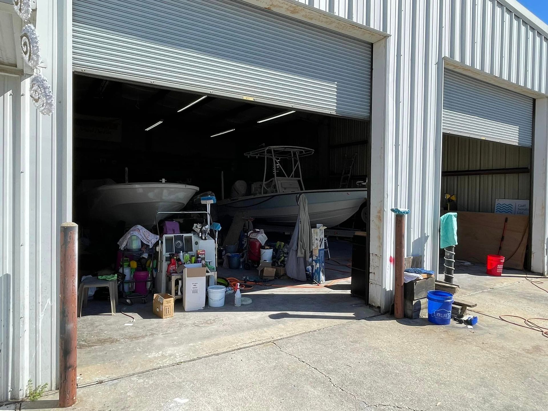 Open garage bay with boats and supplies inside an industrial building