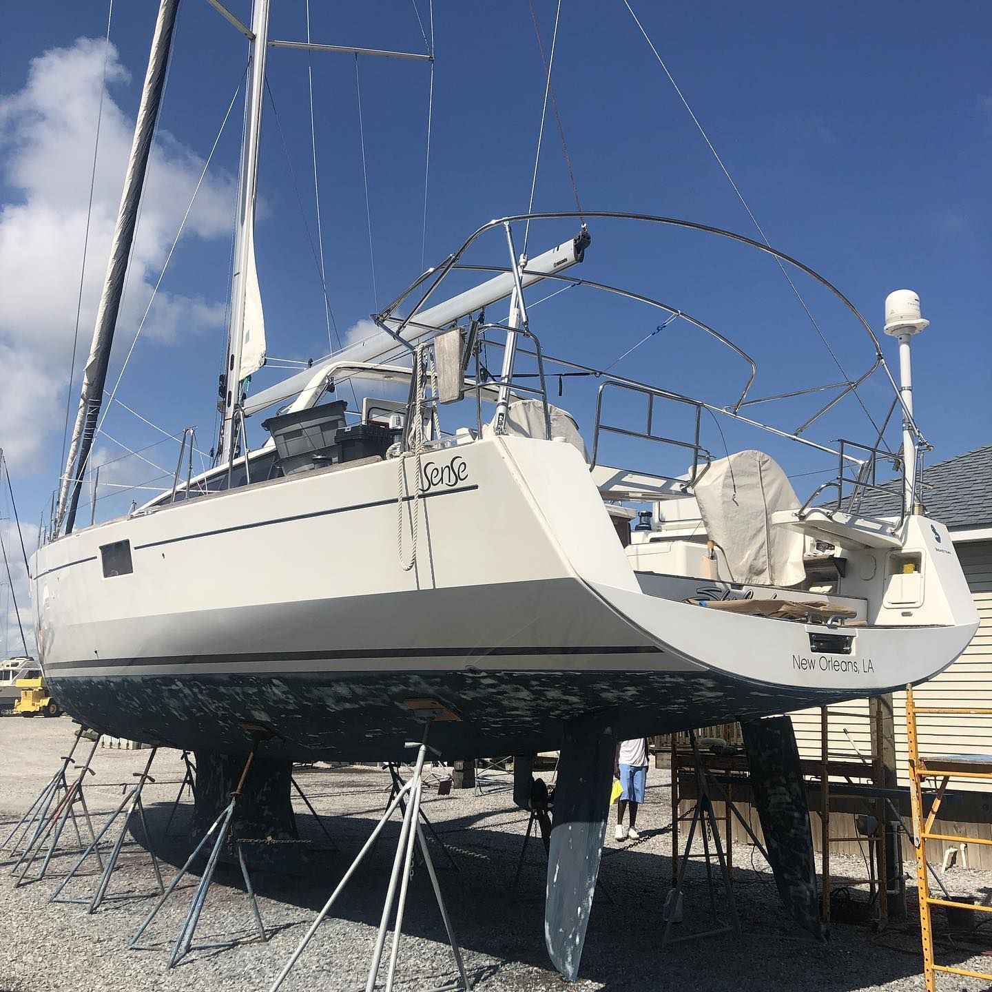 White sailboat on metal stands in a boatyard under a blue sky