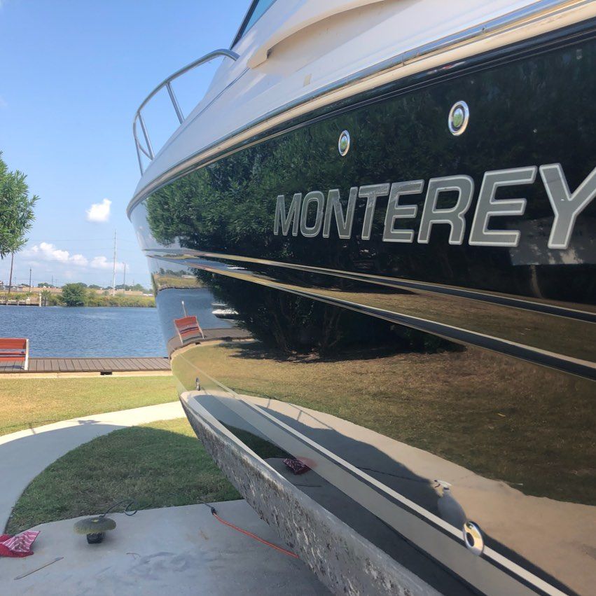 Close-up of a black Monterey boat hull by the water on a sunny day.