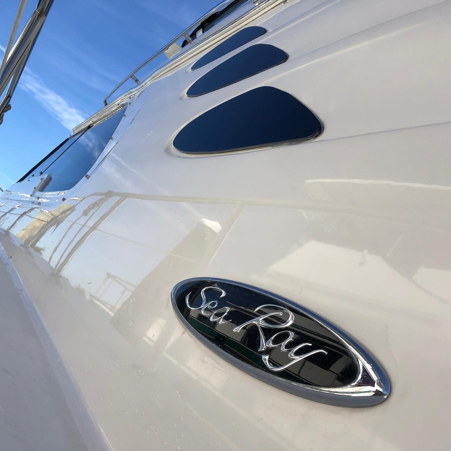 Close-up of a white Sea Ray boat hull with dark blue accent windows and logo.