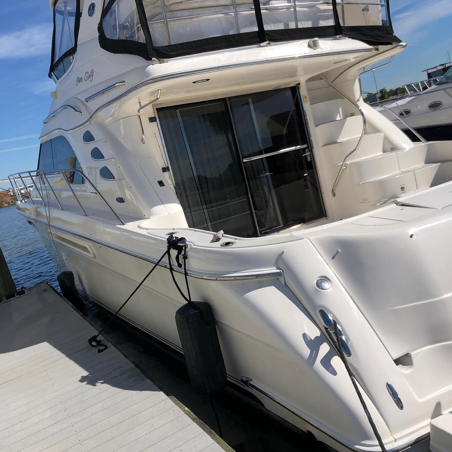 White yacht docked at a marina, viewed from the side with tinted windows and railings.