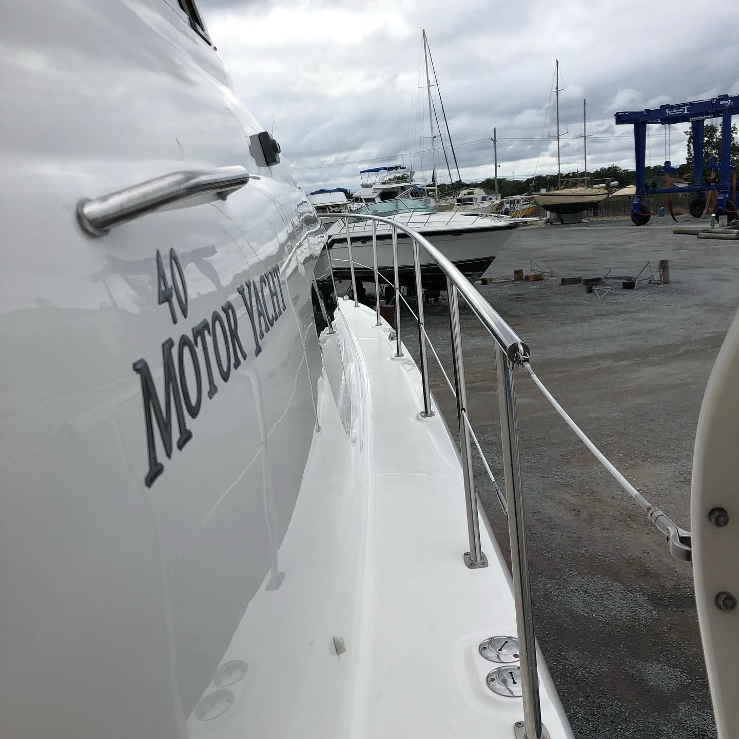 White boat deck with railings, docked marina view, and “Mombo R…” lettering on the hull