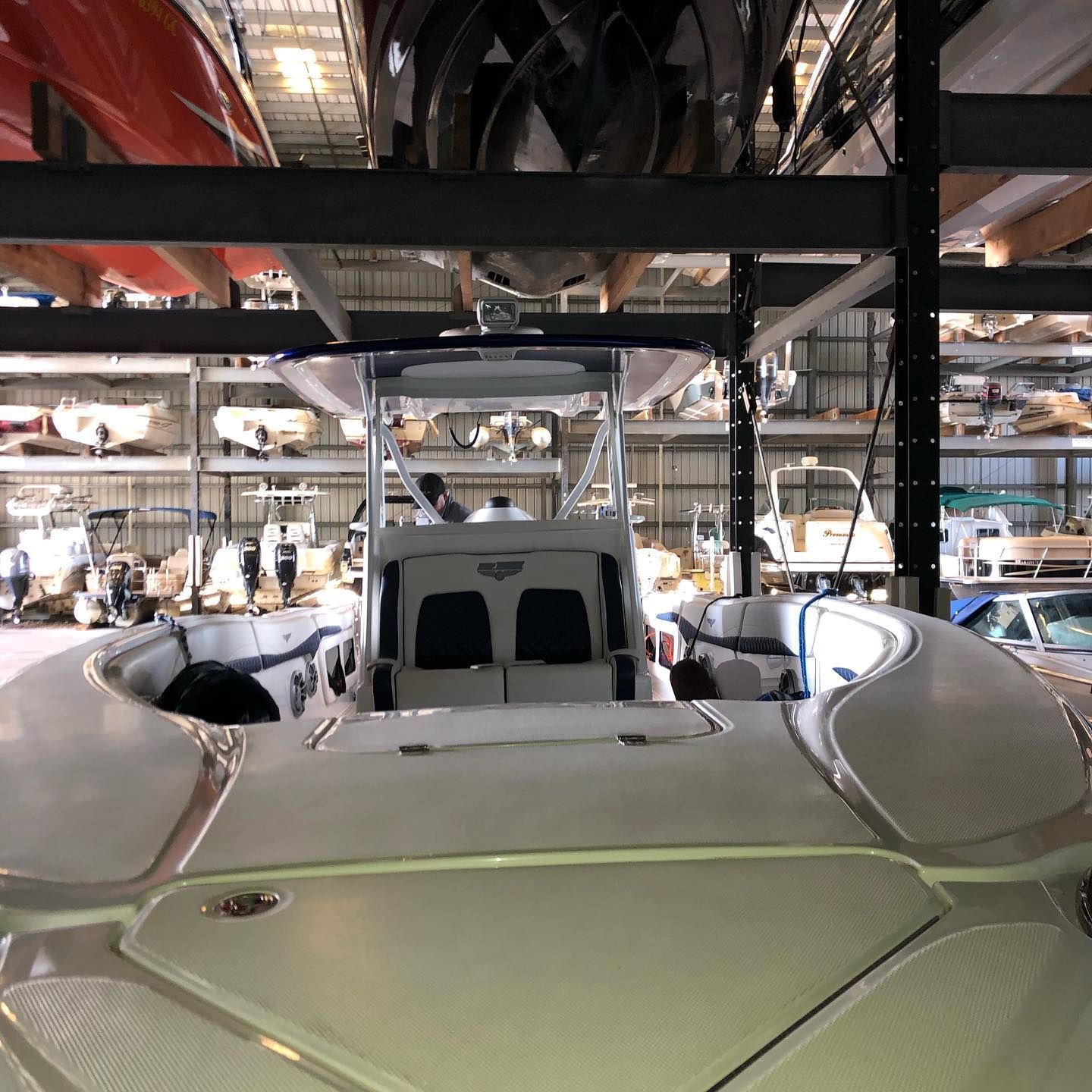 White sports car in a garage, viewed from the rear with industrial beams overhead.