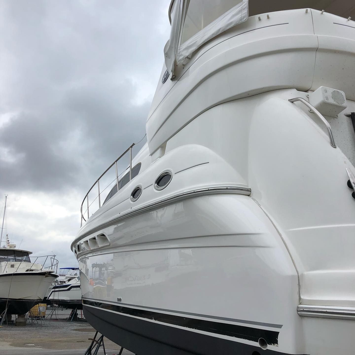White luxury yacht viewed from the stern at a marina under cloudy skies