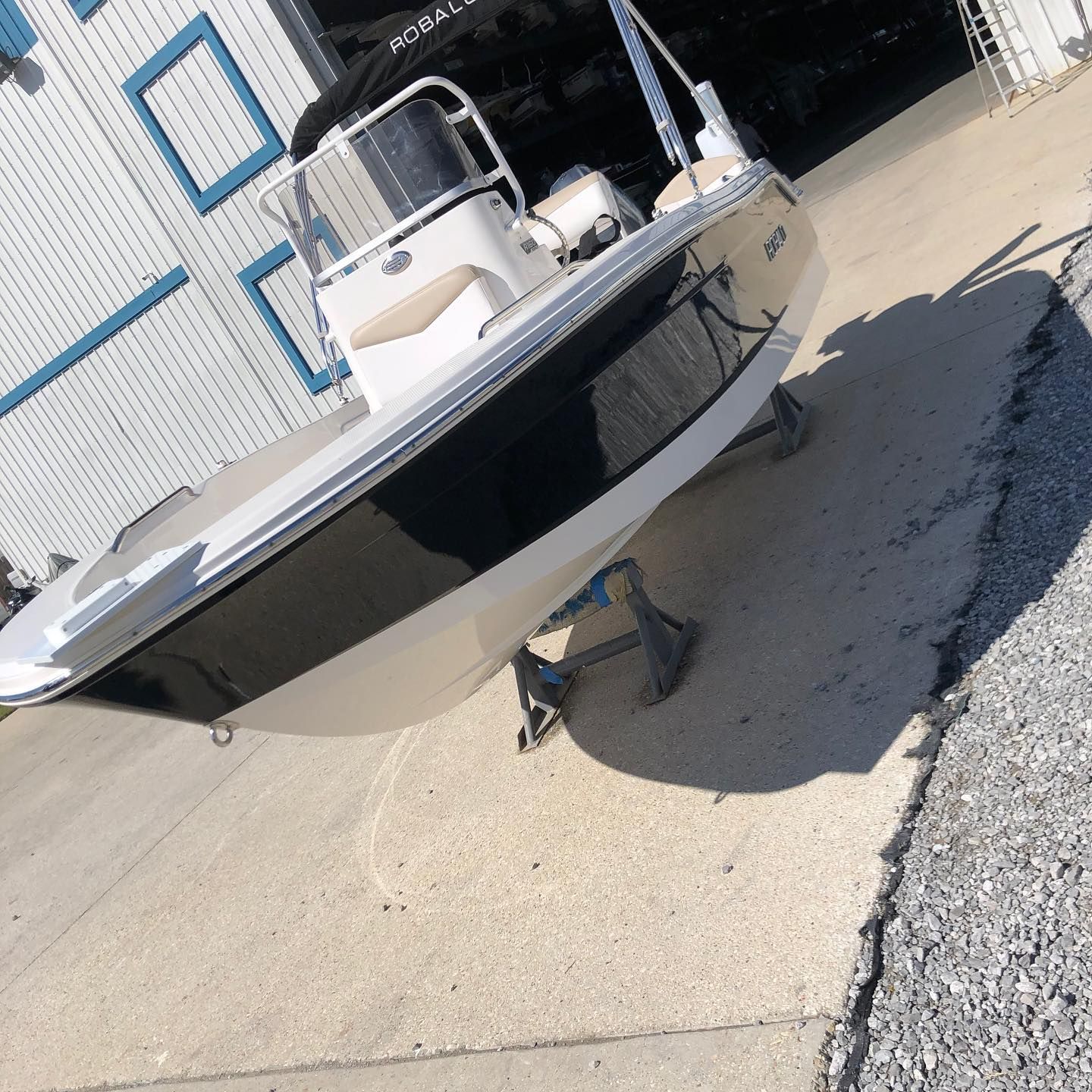 Black-and-white motorboat on a trailer outside a building, parked on a sloped concrete lot.
