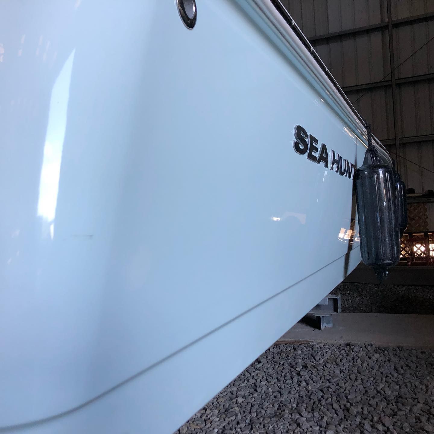 Close-up of a white Sea Ray boat hull inside a warehouse, resting on gravel