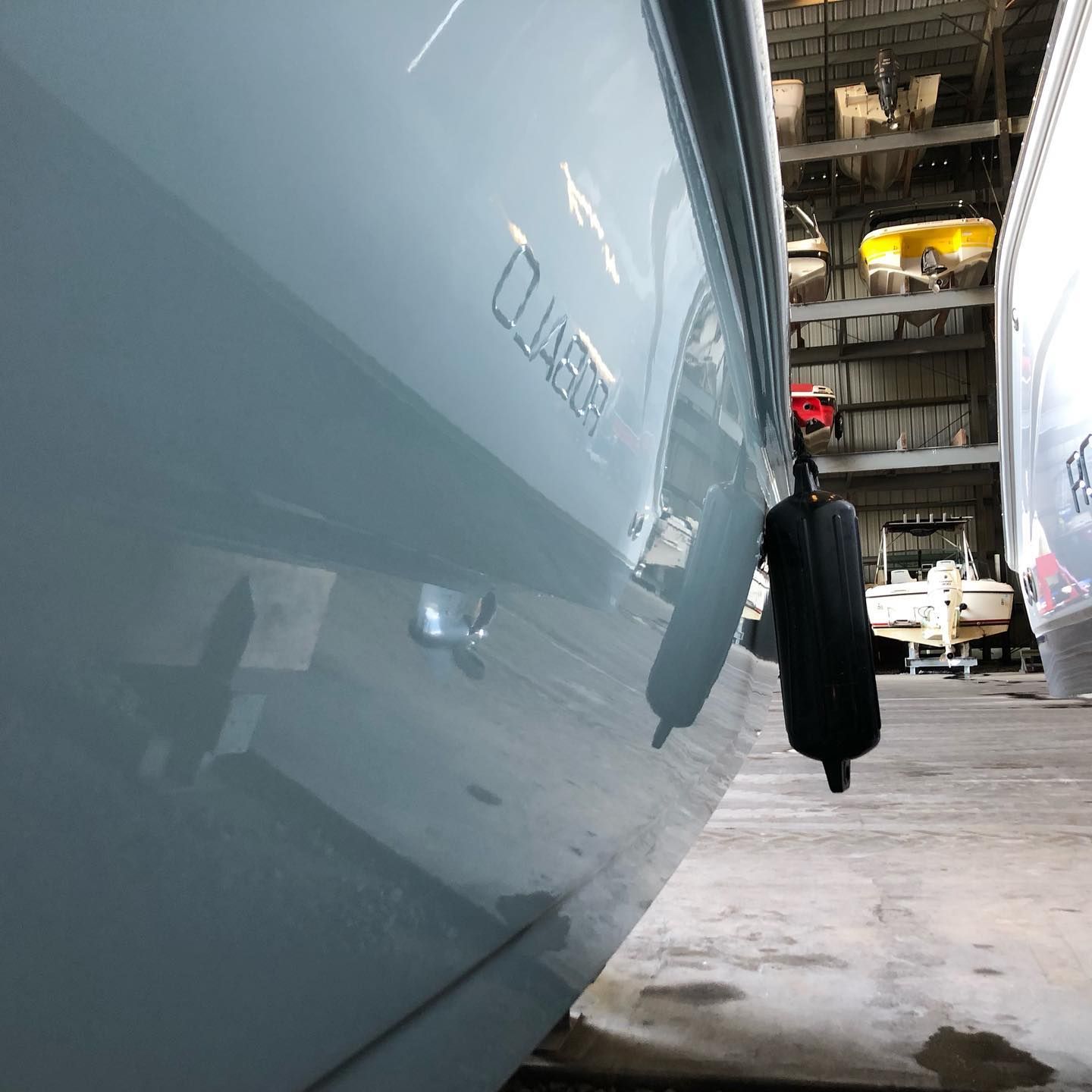 Blue car in a garage, close-up of a side panel with a hanging black cover.
