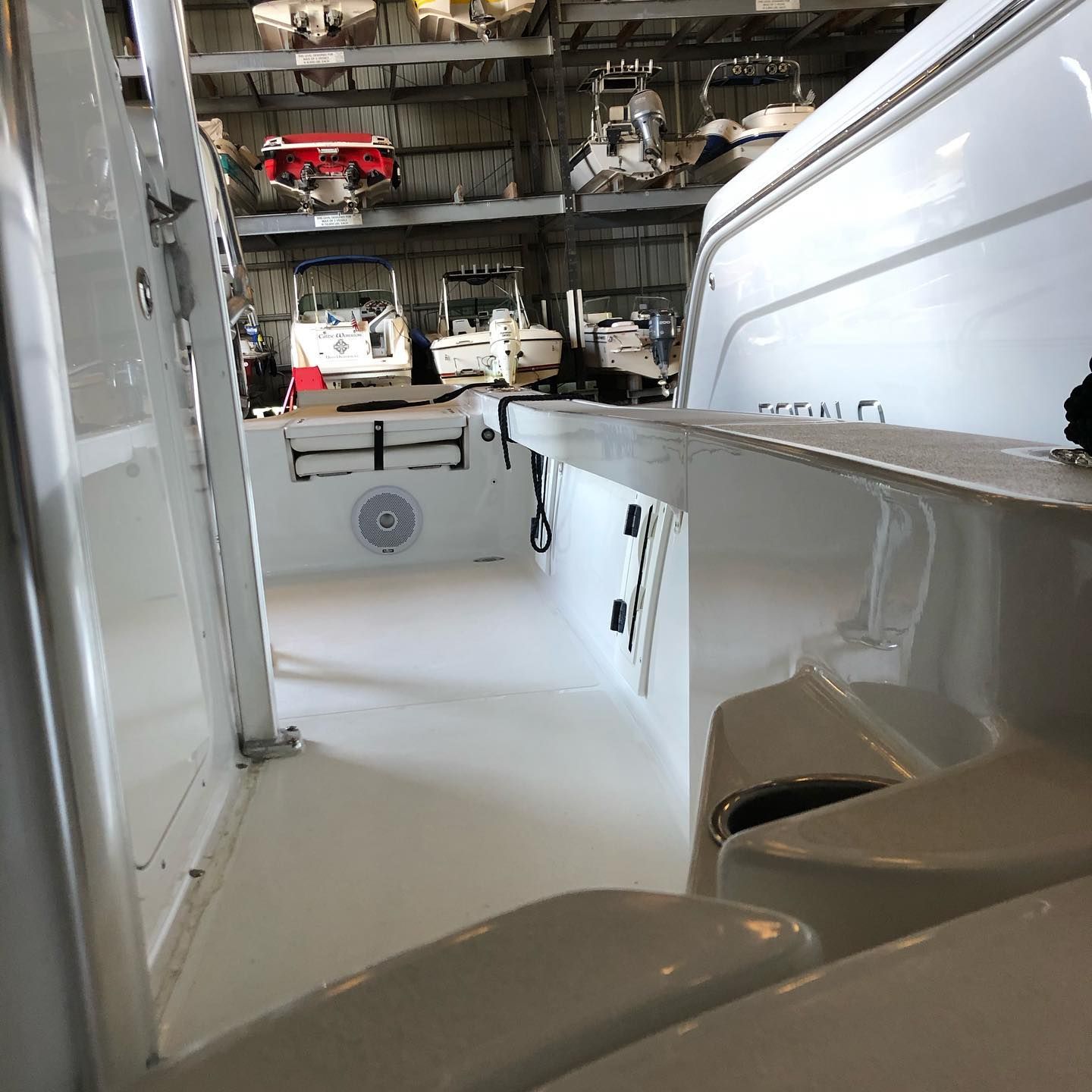Inside a white boat cabin, looking toward the helm and deck with storage and equipment visible.