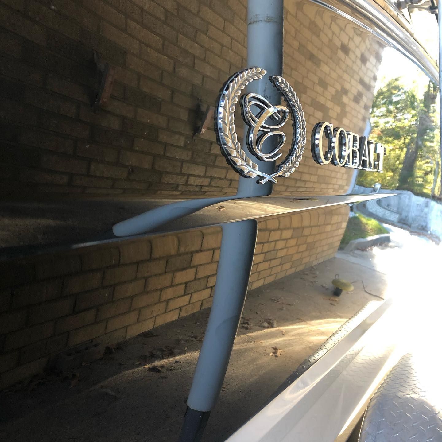 Metal sign with a circular logo mounted on a brick wall outside a building.