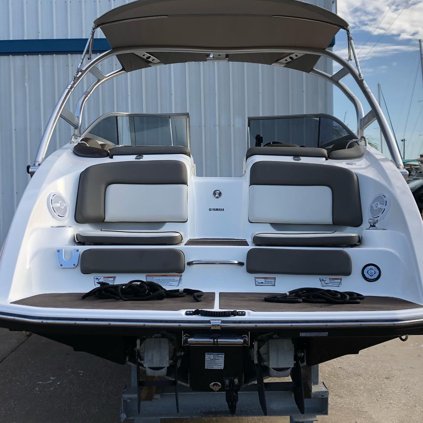 Rear view of a white speedboat with tan canopy and gray seating on a trailer outdoors