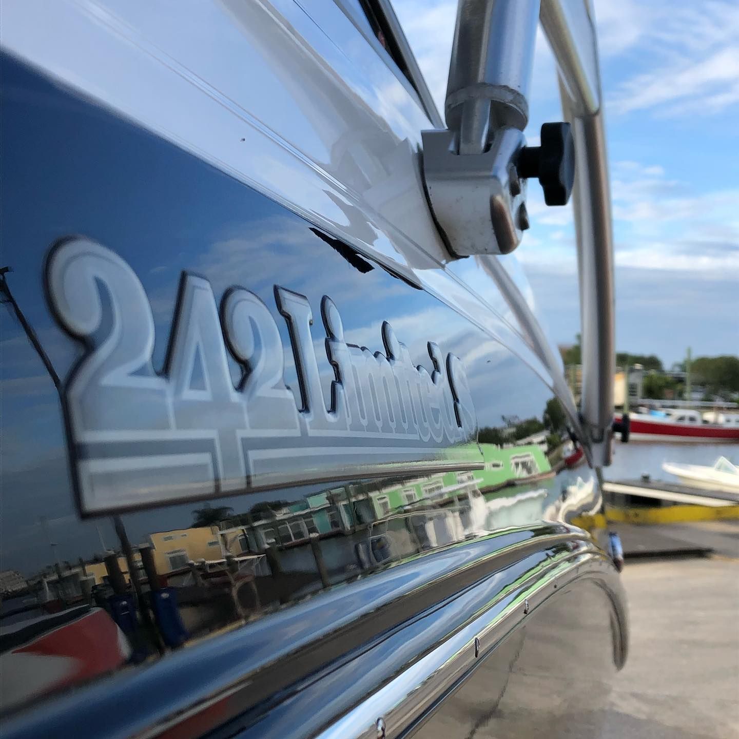 Close-up of a shiny boat hull with the number 2491, reflecting the marina and sky