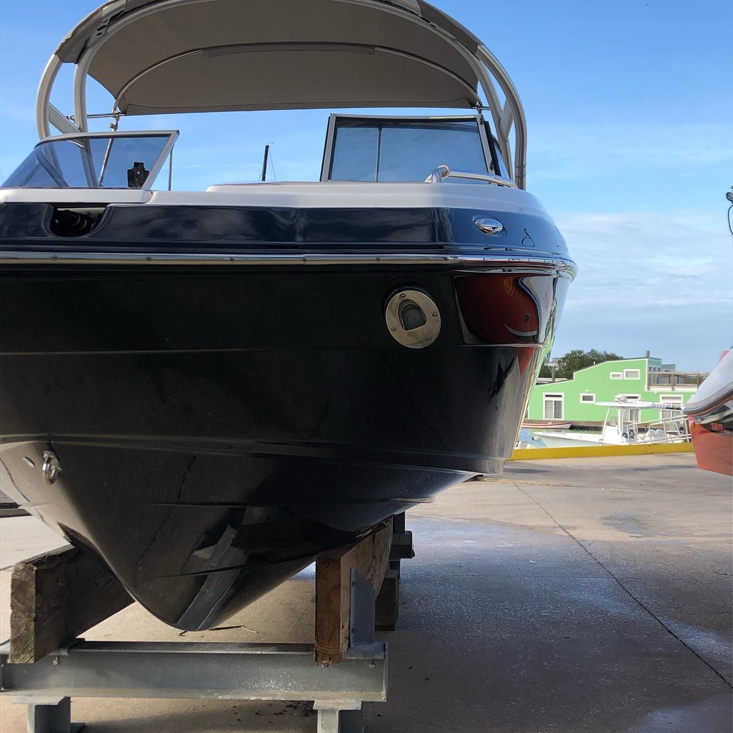 Black boat on blocks in a boatyard, viewed from the bow with a canopy overhead