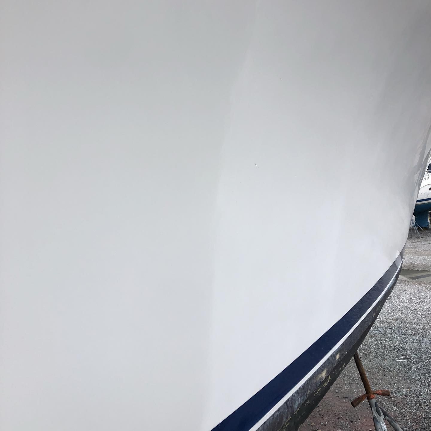 Close-up of a white boat hull with a dark blue stripe along the waterline.
