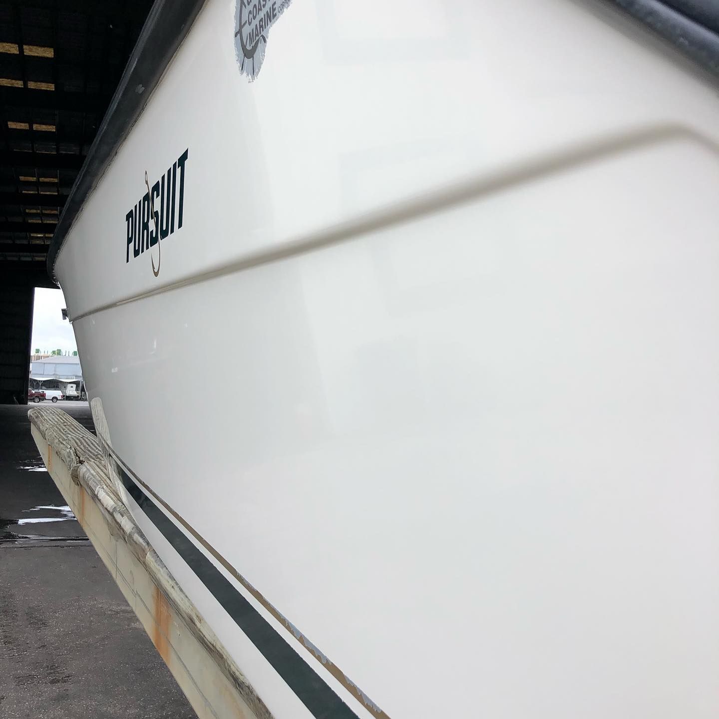 Close-up of a white boat hull with black striping docked beside a pier.