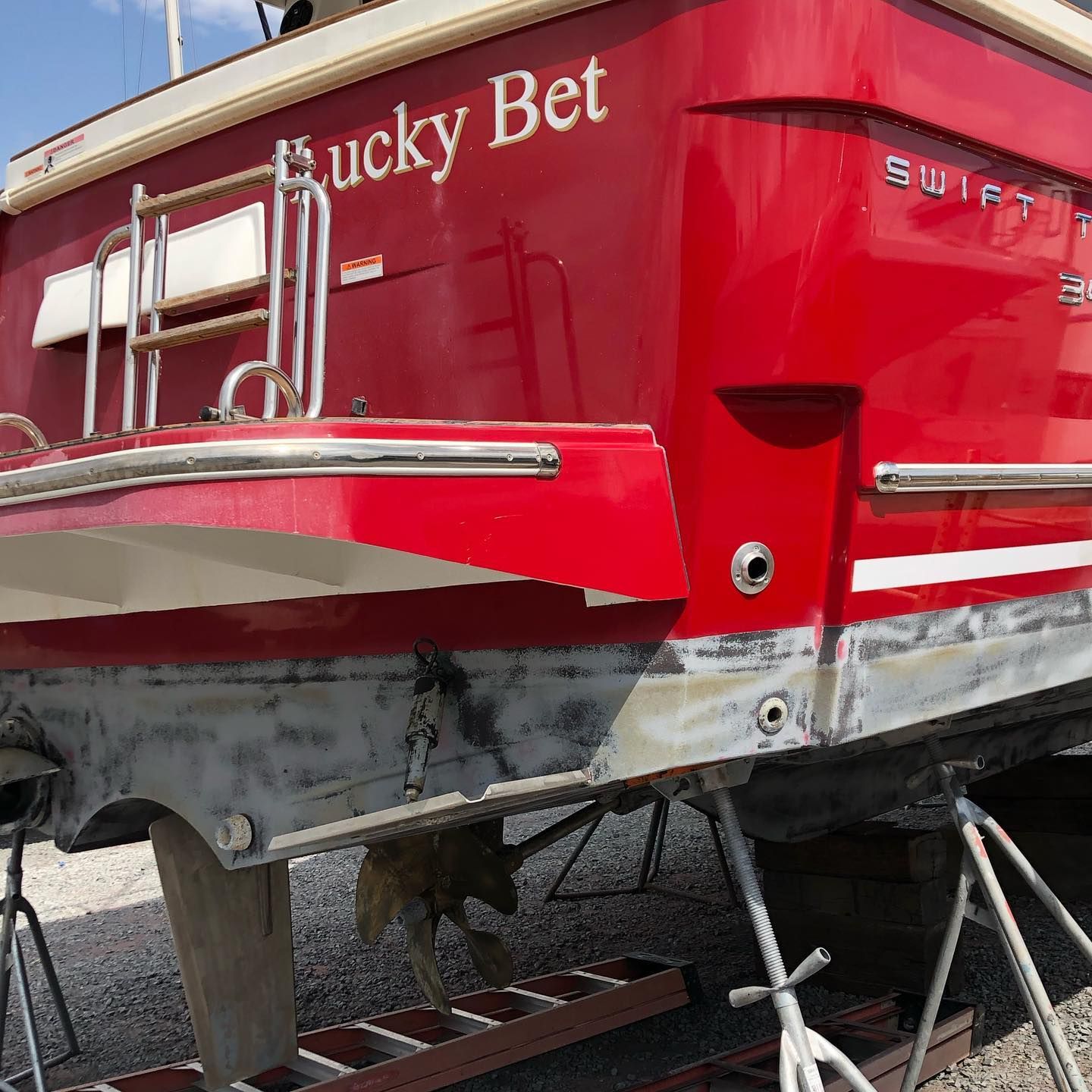 Red Lucky Bet boat stern with chrome railings, docked on a trailer