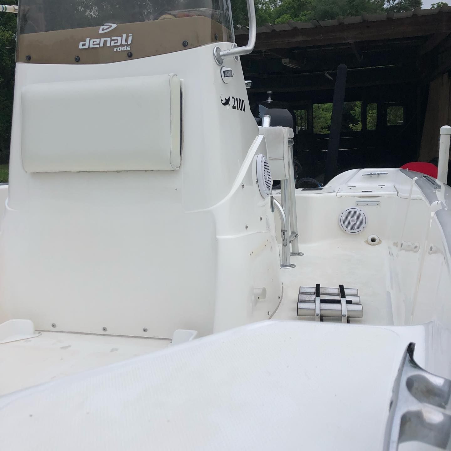 White boat cockpit and seating area with denim upholstery under a covered dock.