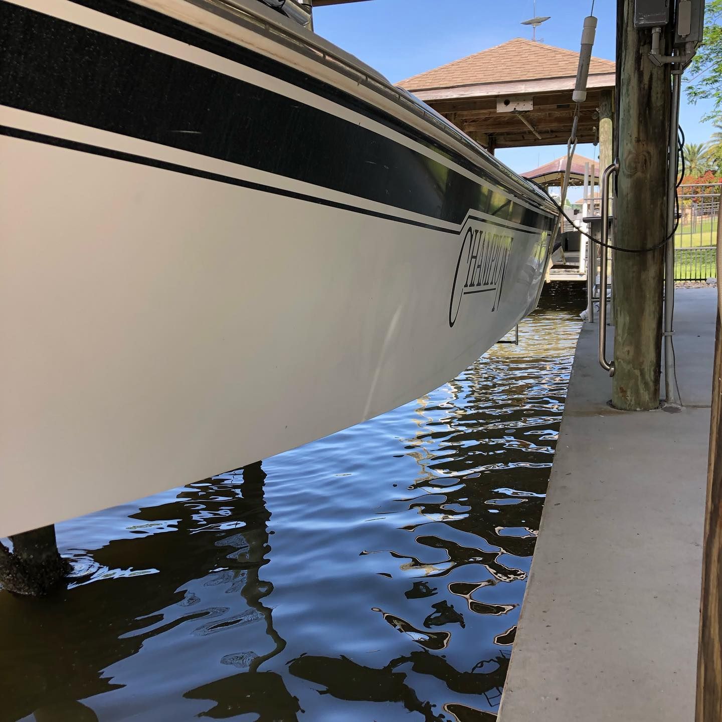 Boat hull beside a dock over rippling water, with a covered walkway in the background