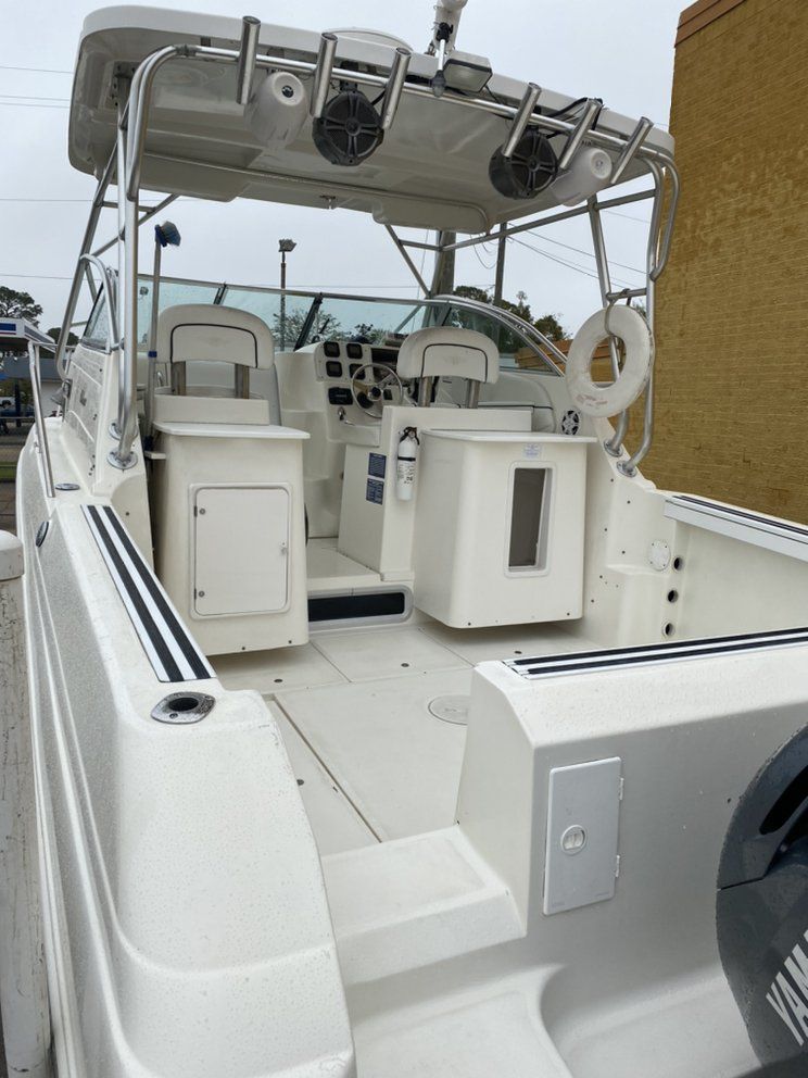White fishing boat cockpit with center console, seats, rod holders, and canopy on deck