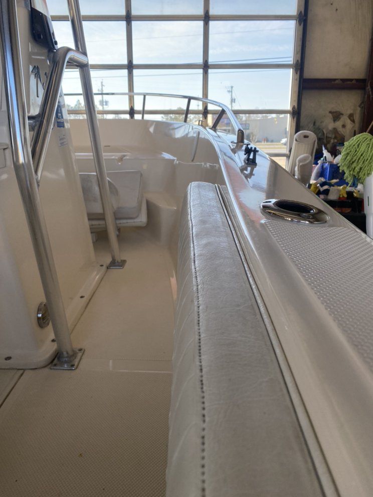 Inside a ferry cabin, a long bench with a textured floor and large windows overlooking the water.