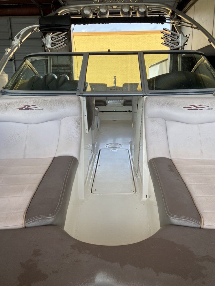 Interior of a boat with white-and-gray seats, center walkway, and open rear view to the water.