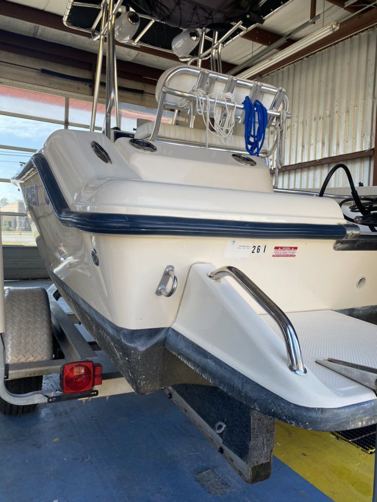 White boat on a trailer inside a boat shed, with blue trim and a metal railing on top