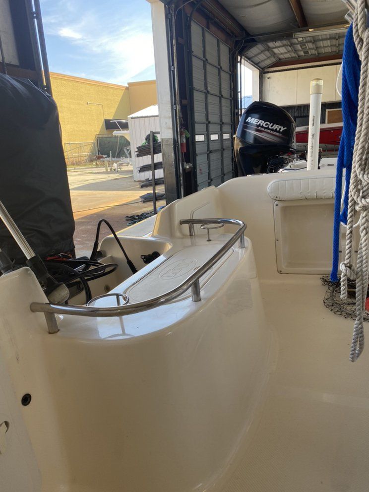 Boat cabin with white seats and black outboard motor at a dock, viewed from inside the open doorway