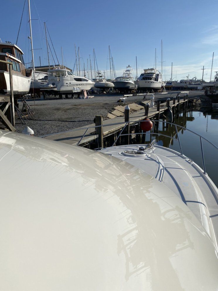 Yacht deck overlooking a marina with docked boats and calm water under a clear blue sky