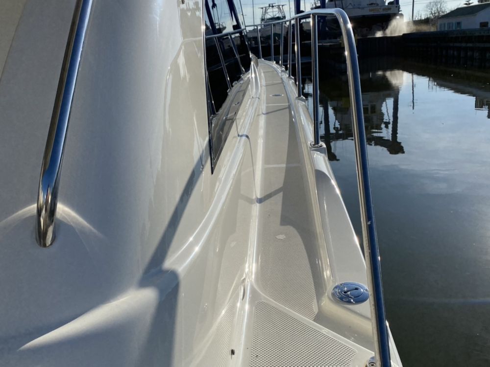 Narrow boat deck along calm water, with metal railings and docked boats in the background.