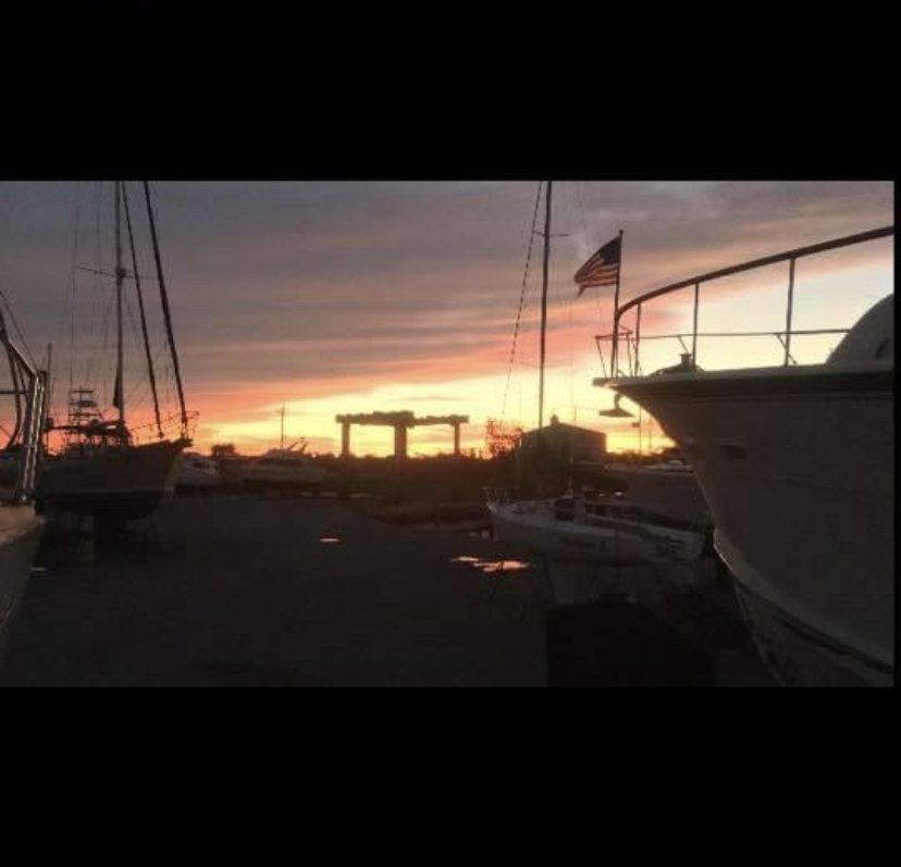Sunset over a marina with boats silhouetted against a pink-orange sky