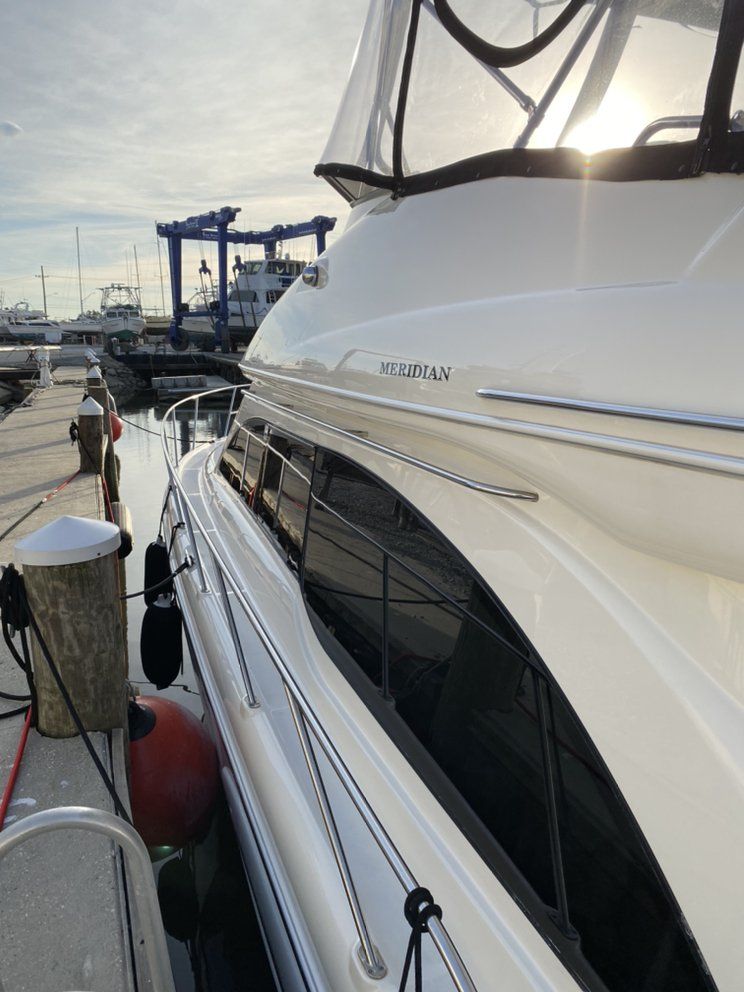 White yacht docked at a marina beside harbor cranes at sunset