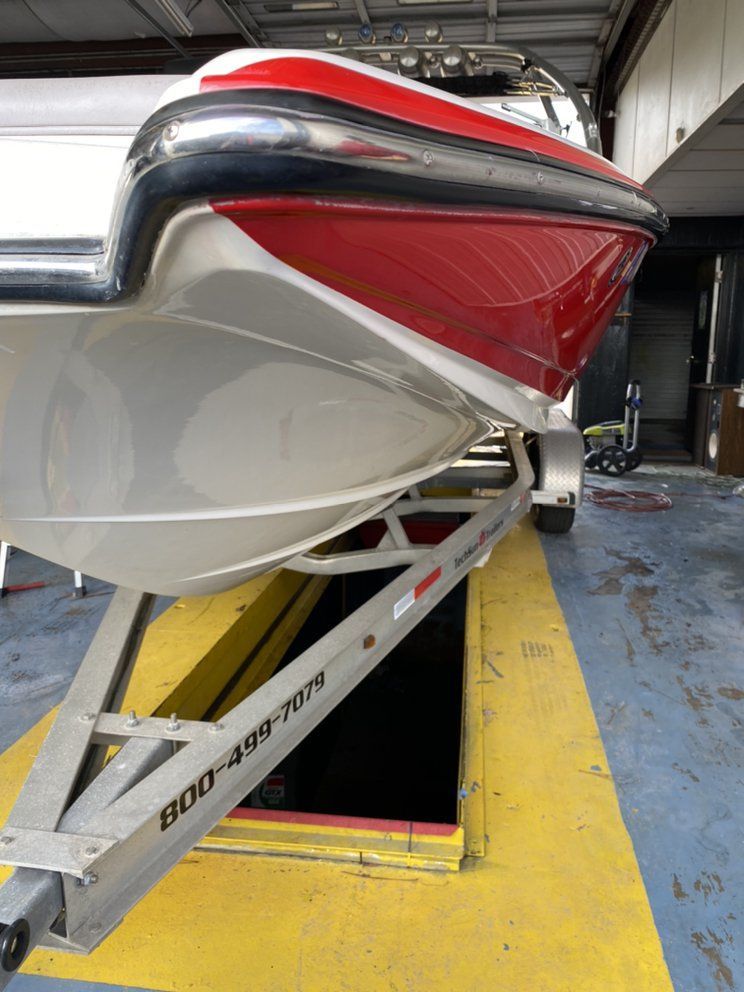 Red-and-white boat hull on a trailer inside a repair shop or garage