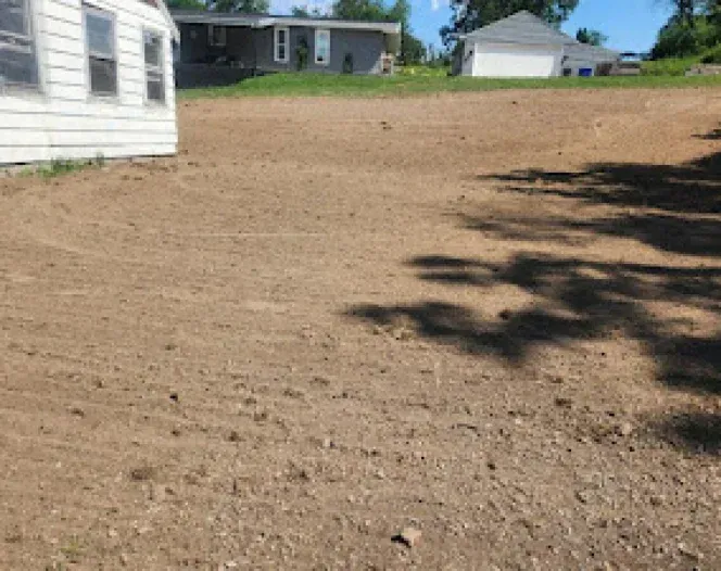 A dirt field with a house in the background.