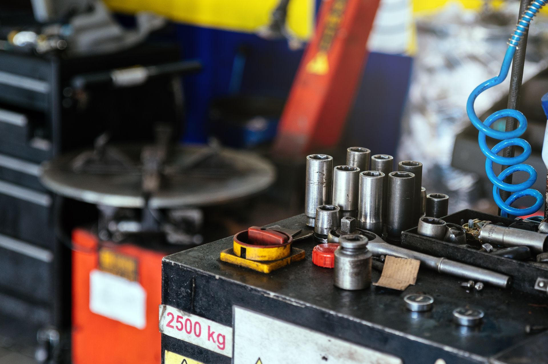 Tools on a workbench in a mechanic's garage, including sockets and a red jack. Tools on a workbench in a mechanic's garage, including sockets and a red jack.
