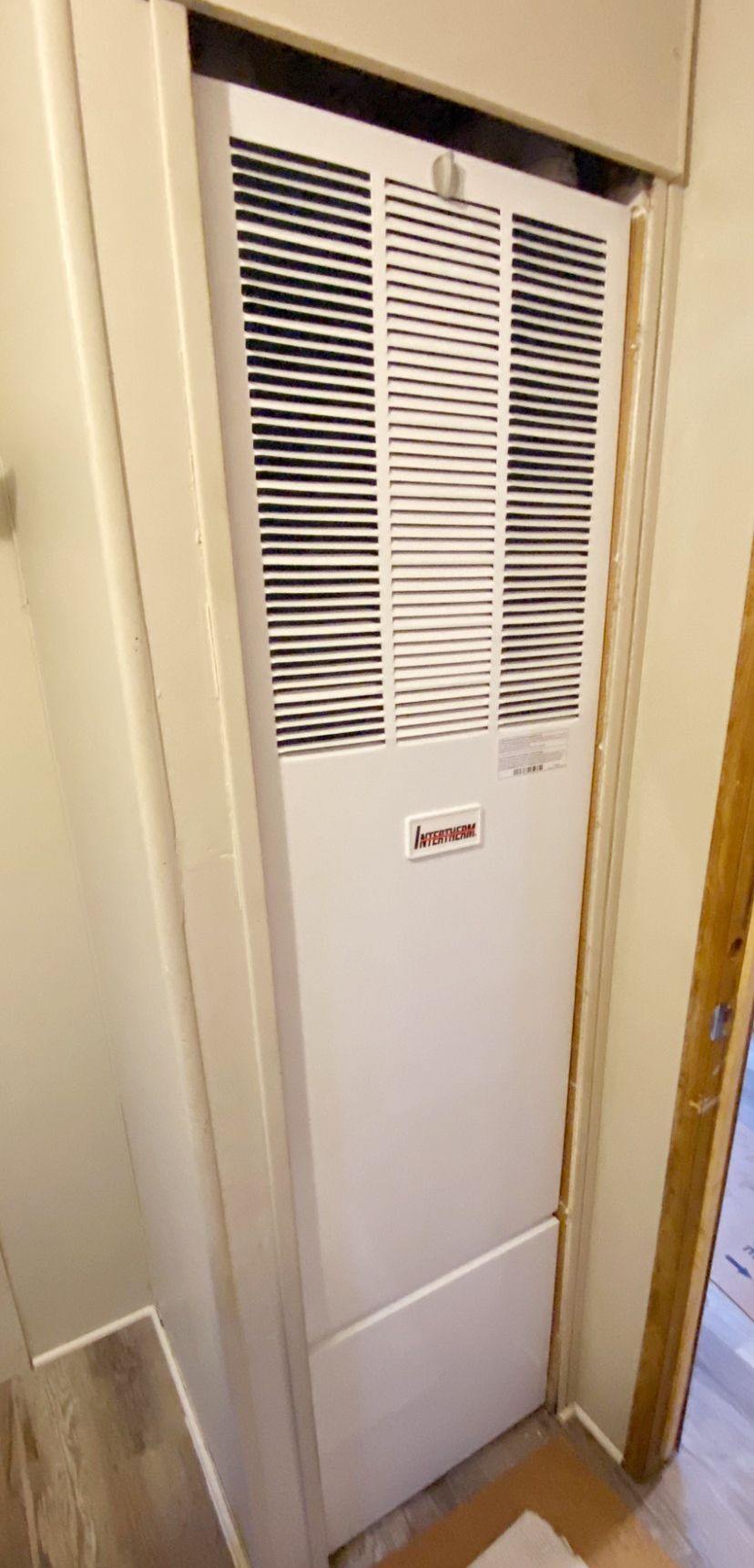 White wall-mounted vented heater in a narrow hallway or closet space