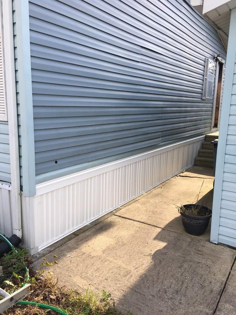 Narrow side yard between two homes with gray siding, white trim, concrete walkway, and a black planter pot