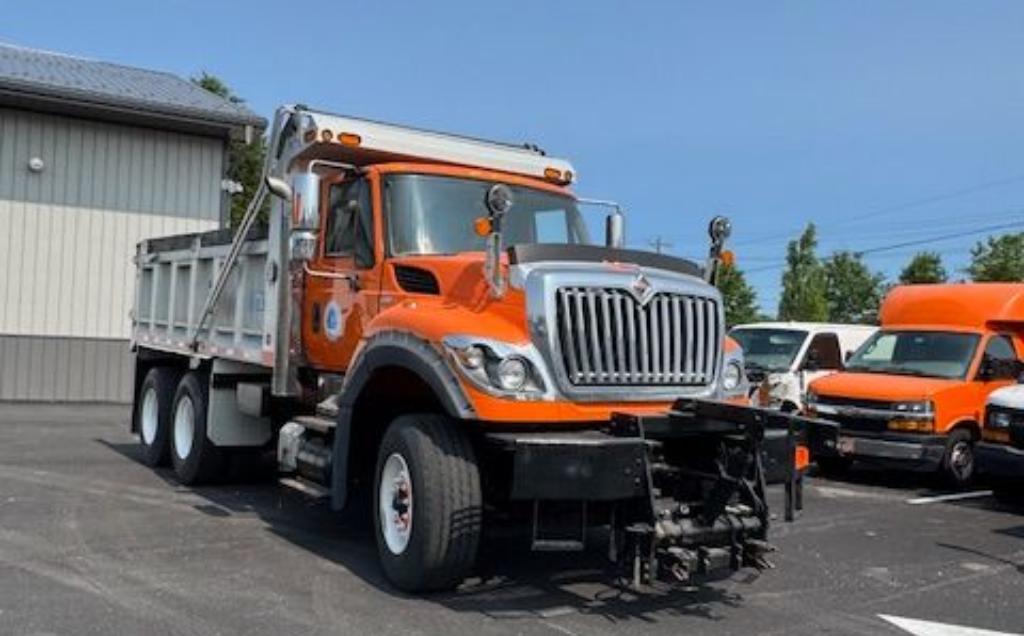 Bright orange dump truck parked outside Betts Garage facility