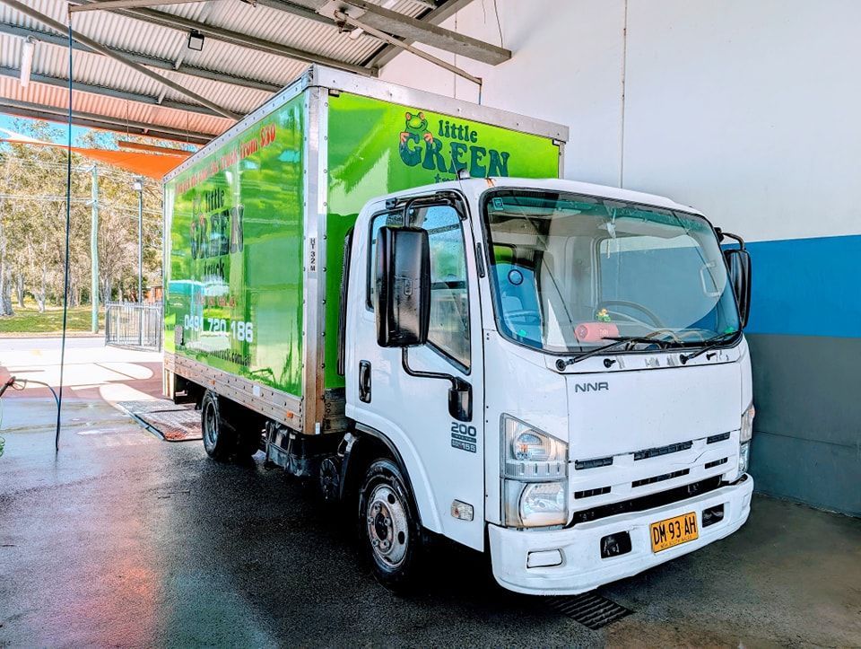 A White Truck With a Green Box on the Back is Parked in a Car Wash — Little Green Truck Port Macquarie in Bonny Hills, NSW