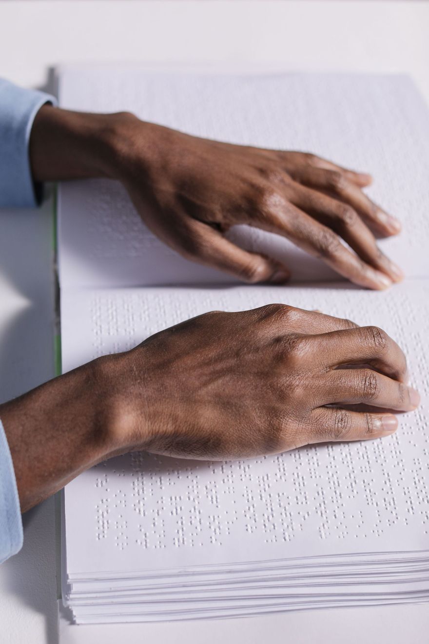 Hands touching braille text on an open page