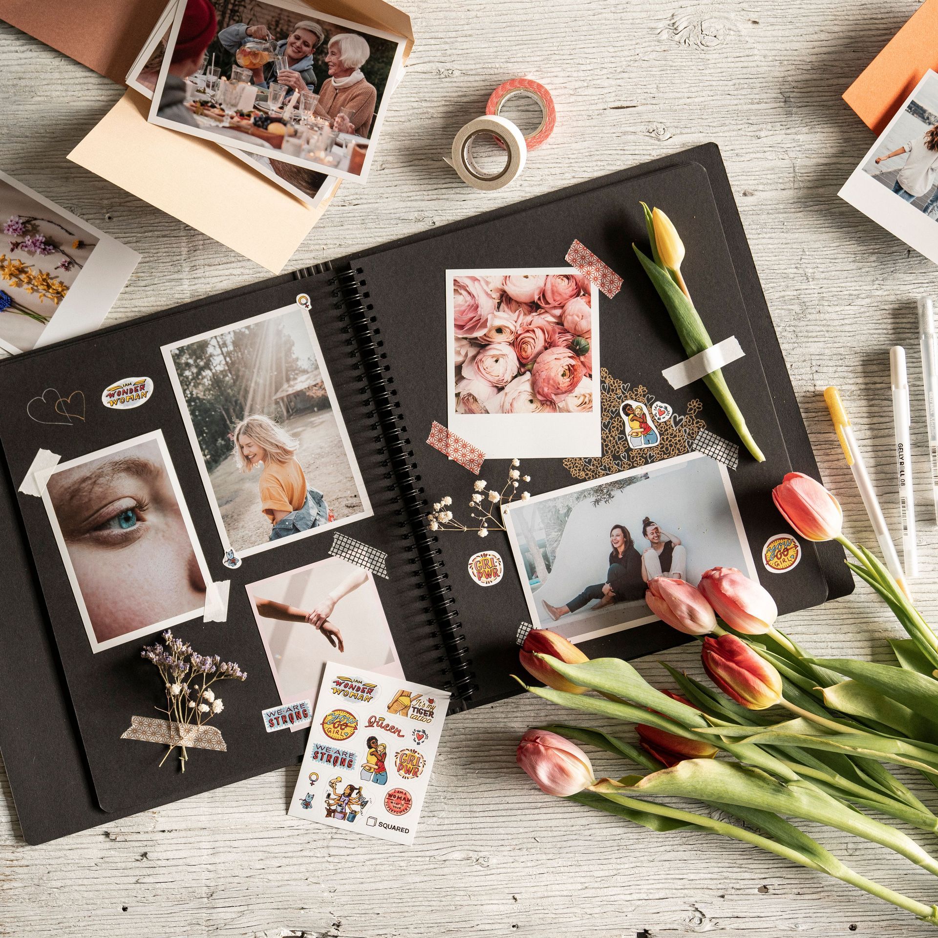 Scrapbook spread with photos, flowers, and craft supplies on a light wooden table
