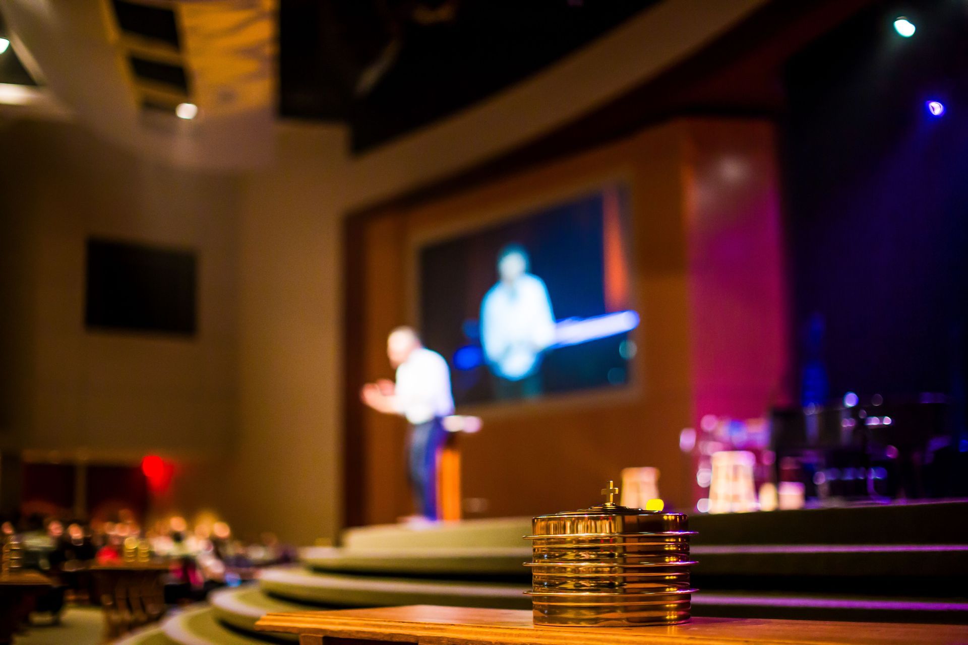Empty auditorium seats with stage lighting, representing speaking engagement venues