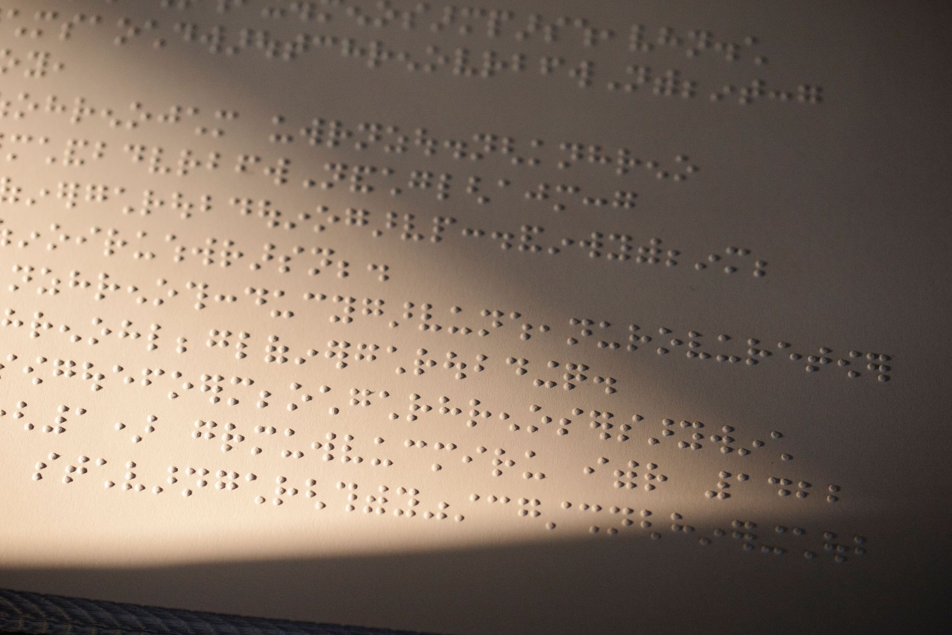 Braille dots embossed on a beige page, lit by soft light.