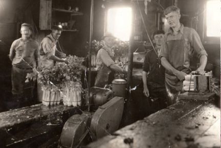 A black and white photo of a group of men working in a factory.