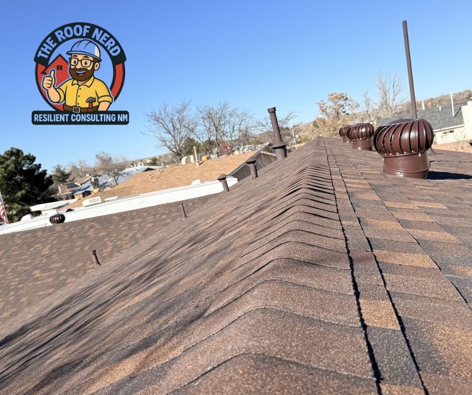 Rooftop view of brown shingles with vent pipes and a clear blue sky