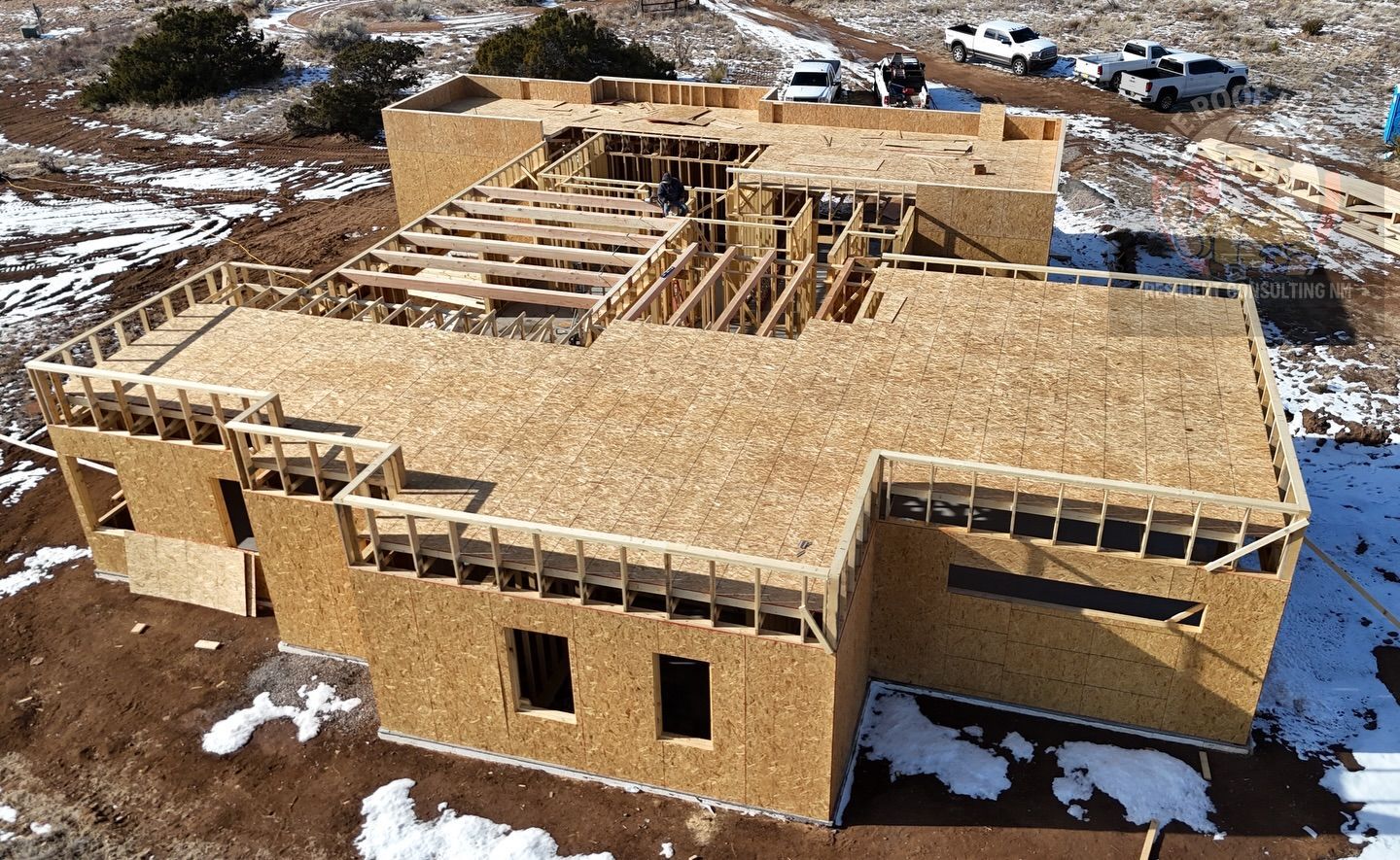 Partially built wooden house with roof framing on a snowy construction site