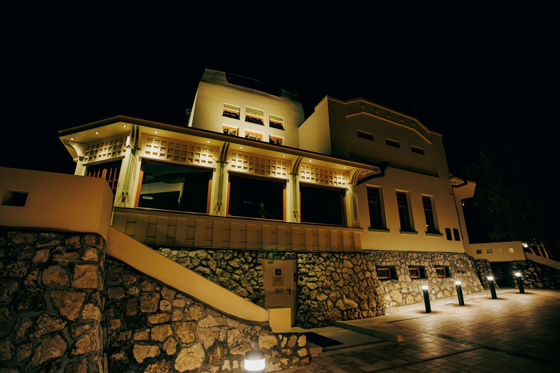 Illuminated stone building at night with columns and a lit walkway