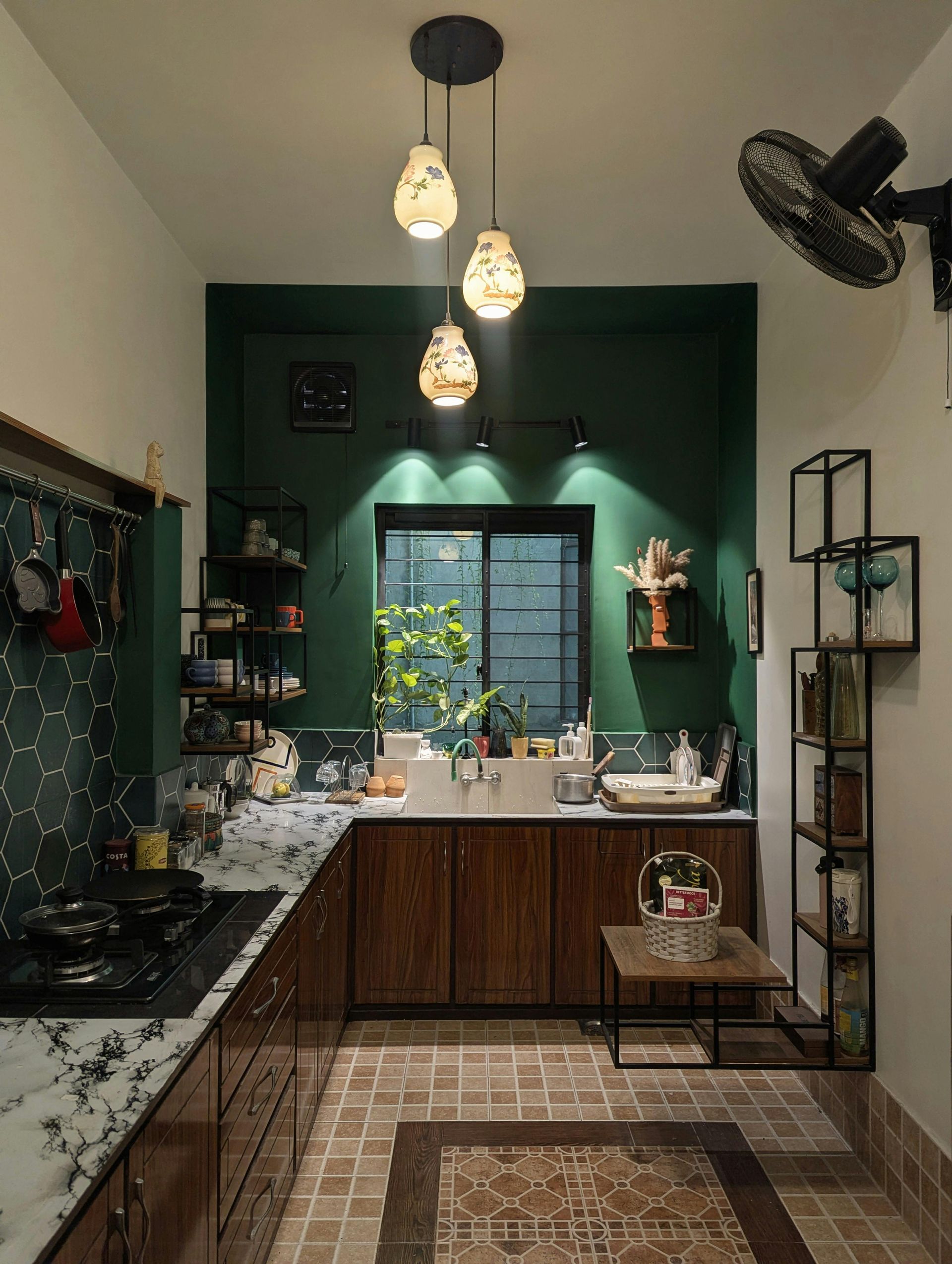 Modern kitchen with dark green walls, wood cabinets, hanging pendant lights, and a patterned runner rug.