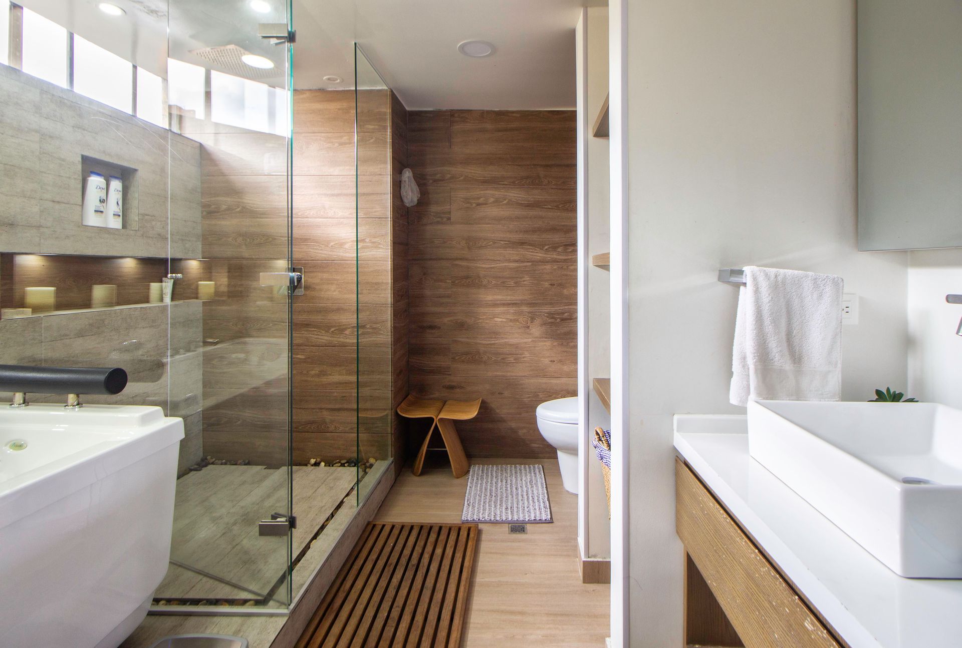 Modern bathroom with glass shower, white vanity, and wooden accents