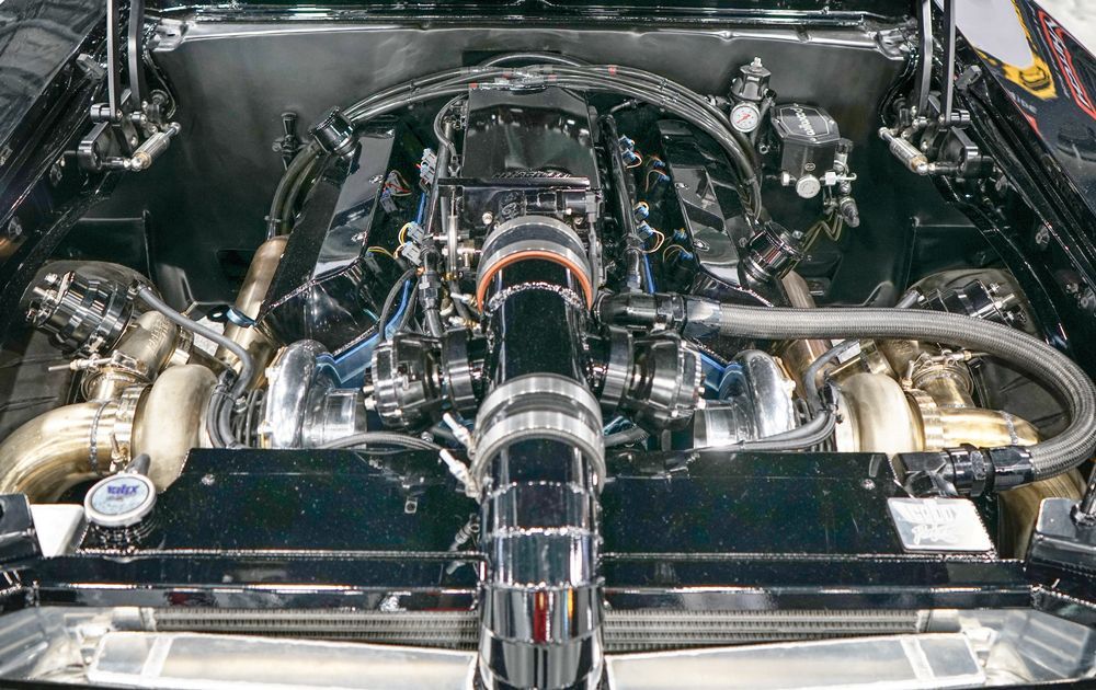 Shiny car engine with dual turbos, surrounded by polished metal components.