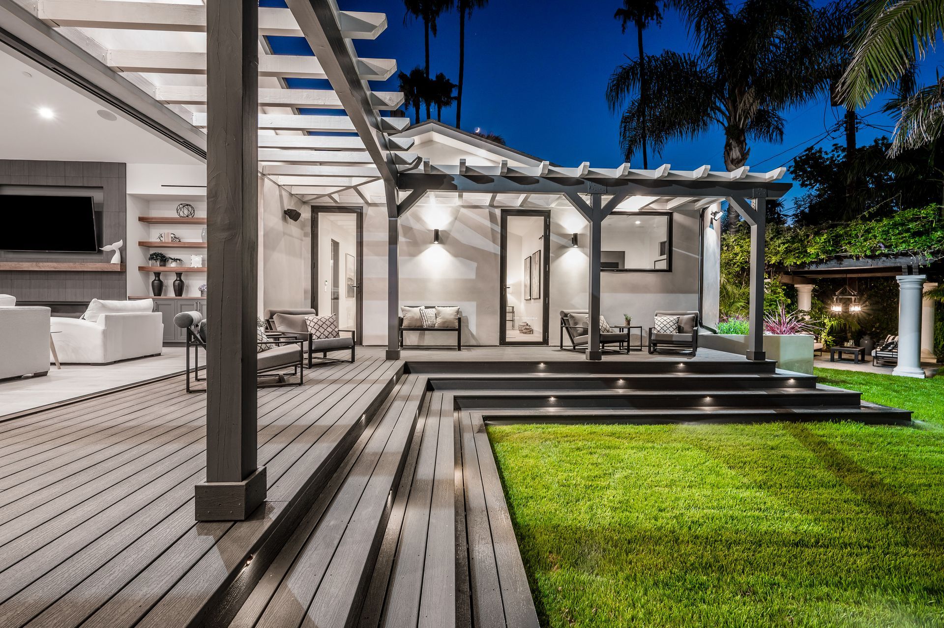 Wooden deck with steps, a raised platform, and stone pathway leading to a house with sliding glass doors. Wooden deck with steps, a raised platform, and stone pathway leading to a house with sliding glass doors.