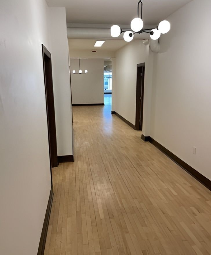 Empty room with light wood floors and white walls, brown trim.